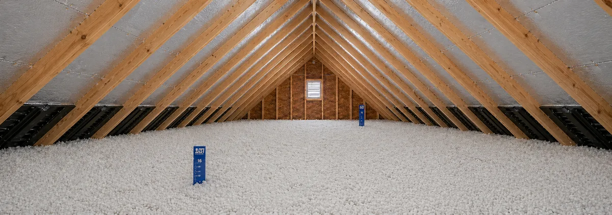 Symmetric attic interior with peaked rafters and a deep, even bed of newly blown-in insulation across the floor, marked with depth rulers — Wake County NC home