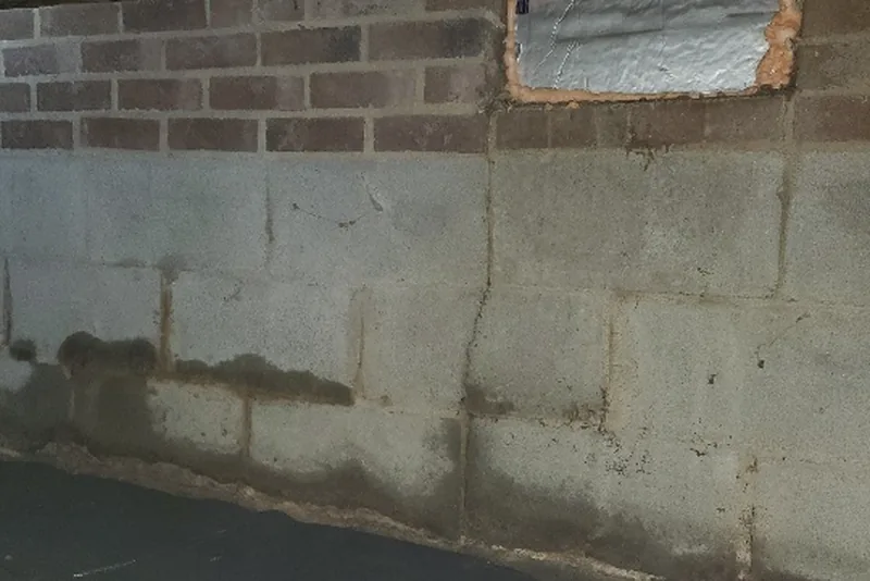 Water staining and moisture damage on a concrete block crawl space foundation wall — visible evidence of the ground moisture that drives up summer humidity in Wake County NC homes