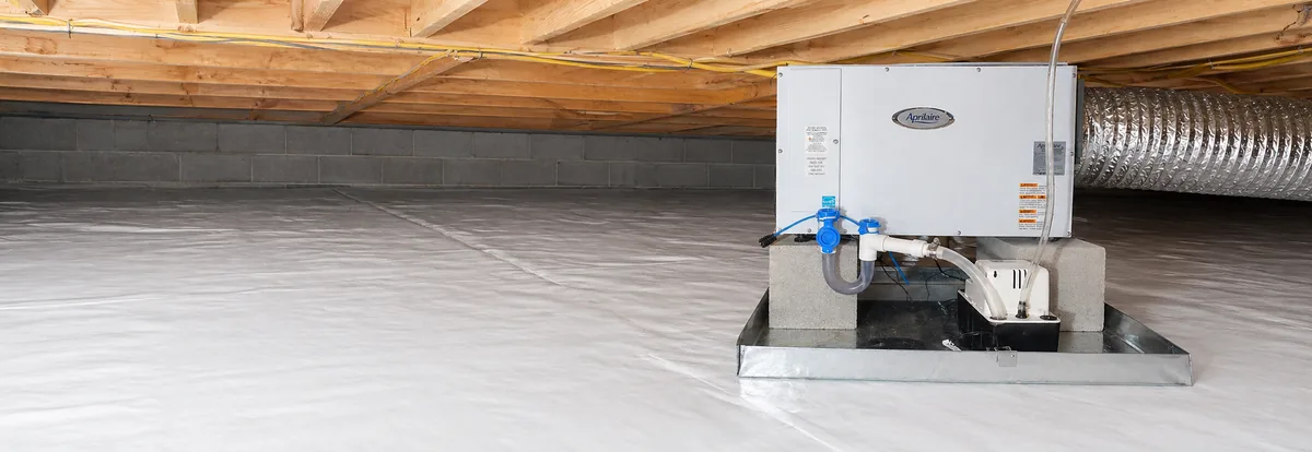 AprilAire crawl space dehumidifier installed on a sealed pad with condensate pump and conditioned ductwork in an encapsulated Wake County NC crawl space